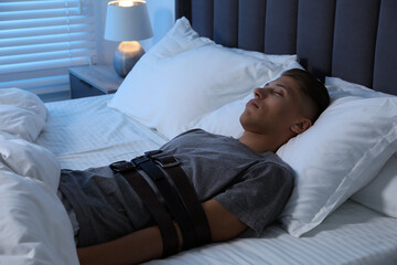 Sleepwalker fastened with belts lying in bed