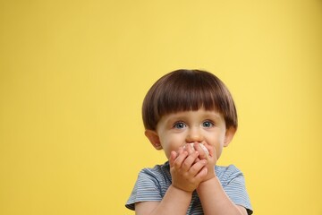 Cute little child eating tasty mochi on yellow background. Space for text