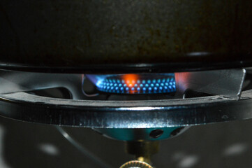 portable gas stove with a blue propane cylinder and a frying pan heating open flam camping...