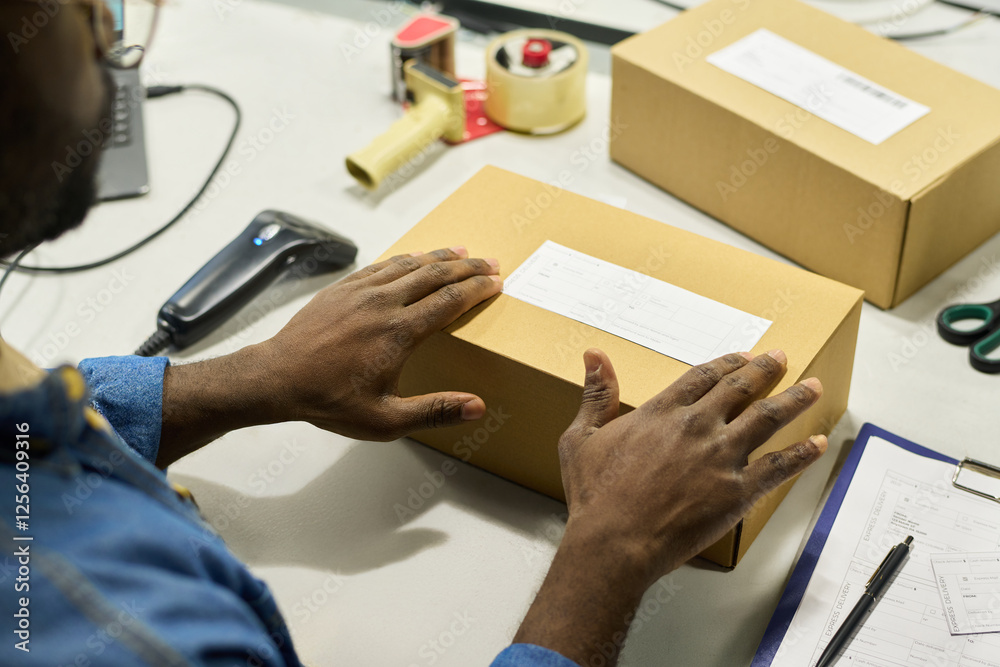 Poster hands of engineer of warehouse putting sticker on top of packed cardboard box with newly produced eq