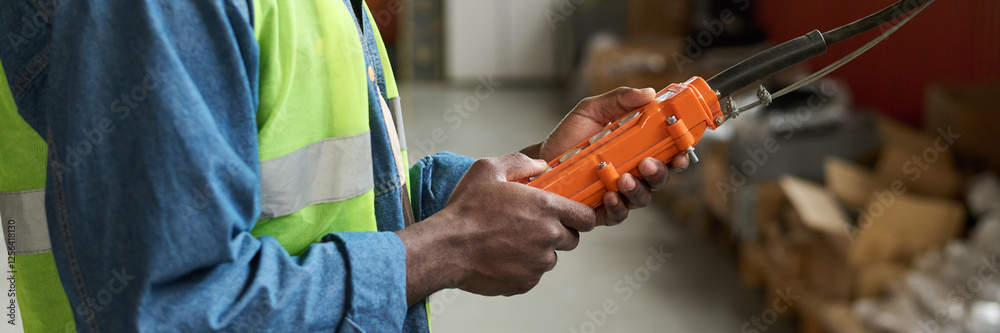Poster Header of hands of young male modern factory worker using control pad while working with industrial equipment in warehouse