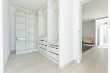 an image of a large white walk in closet in luxury mediterranean bedroom 