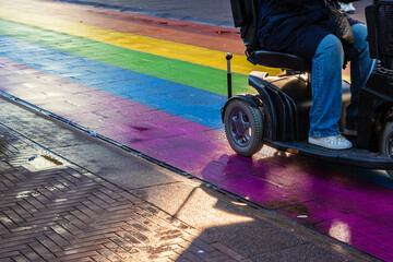 Person using a mobility scooter on a rainbow crosswalk on Regenboogvlag in the Grote Marktstraat....