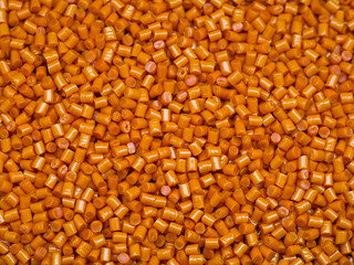 Orange masterbatch granules, isolated on black background, color pigment carrier polymer in plastic...