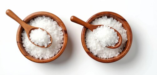 Top view flat lay of sea salt in wooden bowls with spoons isolated on white background. Coarse and fine grained salt crystals. Cooking ingredient, spa mineral for healthy nutrition.