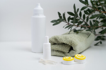 Contact lenses, case and bottle with solution and eye drops on white background. Eye health and care, vision, ophthalmology concept, close-up