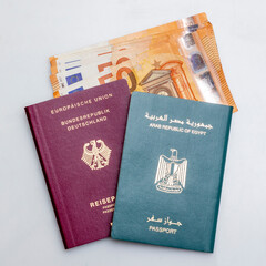 German and Egyptian Passports with Euro Banknotes, Migration Concept, on White Background