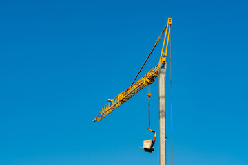 Construction crane lifting materials under clear sky