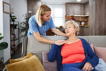 Caring nurse supports elderly woman in cozy living room setting