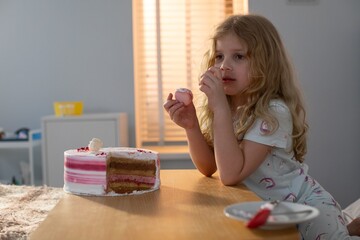 A child is joyfully enjoying a delicious cake while sitting in a cozy and warm room