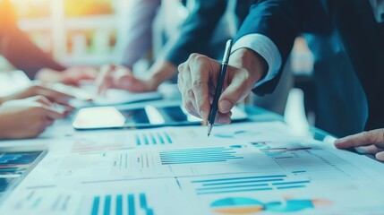 Person pointing a pen at table covered with various papers and documents