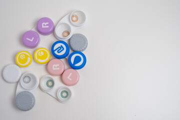 Contact lenses, case and bottle with solution and eye drops on white background. Eye health and care, vision, ophthalmology concept, close-up
