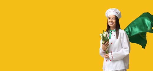 Female chef in superhero cloak holding tulips on yellow background with space for text. International Women's Day celebration