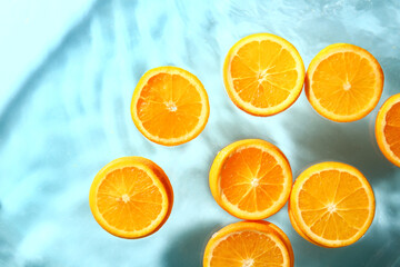 Slices of fresh orange in water on blue background