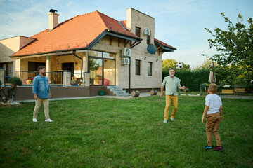 Happy family playing football in backyard of house