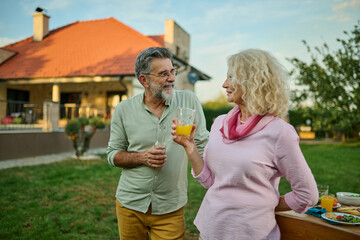 Fototapeta premium Senior couple enjoying drinks in backyard near house