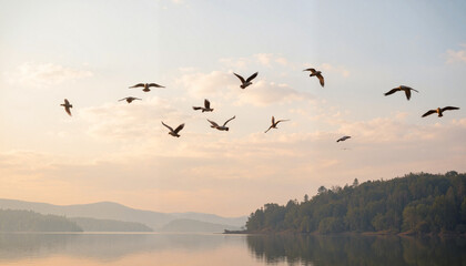 Fototapeta premium Birds flying over a calm lake at sunrise