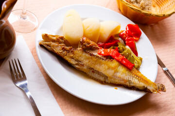 Image of deliciously grilled wrasse fish with peppers and potatoes served on plate