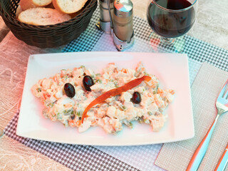 Traditional salad of Spanish cuisine called Ensalada rusa, made from boiled potatoes, carrots, eggs, tuna, seasoned with ..mayonnaise and decorated with olives and a piece of fish on top