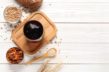 Glass of tasty kvass and ingredients on white wooden background