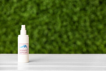 Spray bottle of mosquito repellent on table outdoors