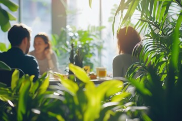 A cozy indoor setting with potted plants and natural lighting, showcasing a casual work environment where two individuals are enjoying a coffee break.