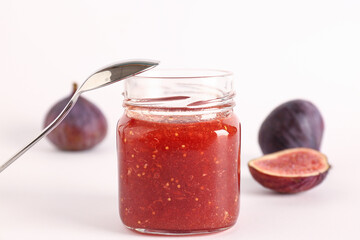 Jar of sweet fig jam on white background