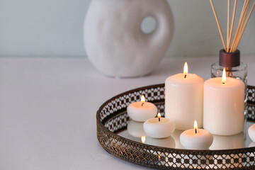 Tray with burning candles on white background