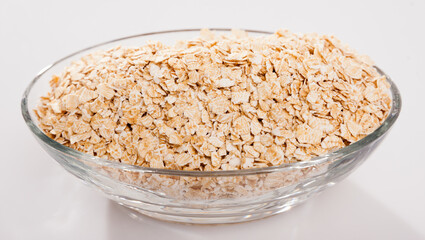Oat flakes in oval glass bowl on white surface. Concept of healthy food..