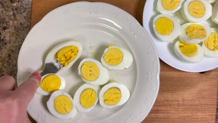 Boiled chicken egg halves with bright yolks are mashed with a fork in a plate. Top view.