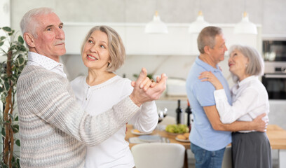 Couples of elderly women and men doing couple dances in kitchen