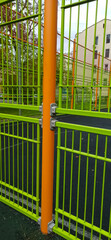 Closed gates on the sports ground.
Bright green metal gate with orange support. Modern fence construction