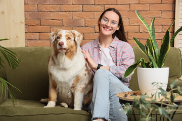 Young woman with cute Australian Shepherd dog and houseplants at home