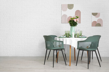 Beautiful table setting for wedding with flowers near white brick wall in dining room