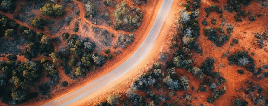 Aerial view of curved road in australian outback landscape with red earth and vegetation