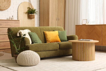 Stylish interior of living room with green sofa, chest of drawers, closet and coffee table