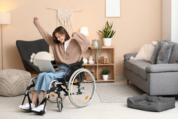 Young pretty woman in wheelchair with modern laptop at home