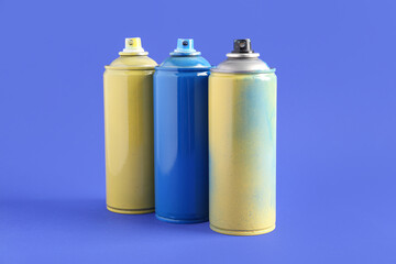 Spray paint cans on blue background