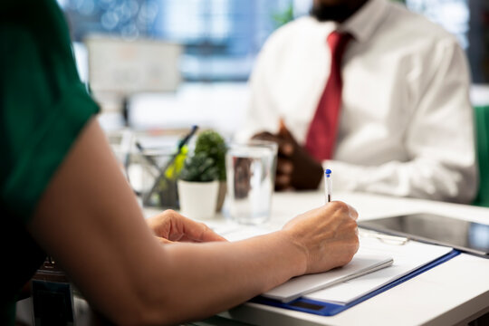 HR employee filling in paperwork after making sure candidate possesses skills needed to fulfil role. HR manager signing contract after evaluating if applicant qualifications align with company values
