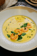 Creamy shrimp soup with spinach, garnished with chili flakes and herb oil, served in a gourmet style