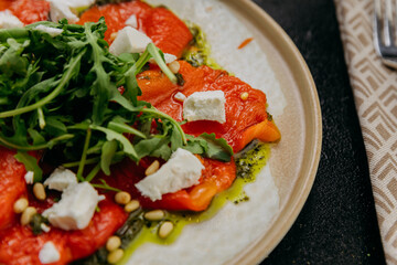 Roasted bell pepper carpaccio with arugula, feta cheese, pine nuts, and pesto, in gourmet style