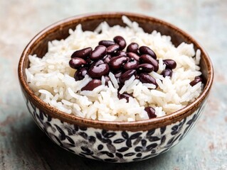 Cooked rice with beans in a bowl. Steamed white rice mixed with black beans in a ceramic bowl. Emphasizing nutrition and cultural cuisine. Ideal for food blogs and health recipes.