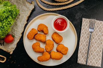 Crispy chicken nuggets with ketchup on plate with fresh ingredients in stylish food presentation