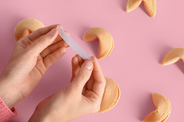 Female hands with blank piece of paper and fortune cookies on pink background