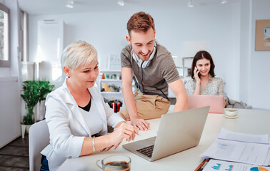 Businesspeople using laptops and team communication while collaborating in an office