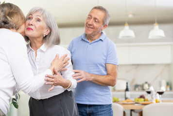 Obraz premium Two elderly women friends hugging when meeting in kitchen