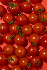 A vibrant collection of fresh cherry tomatoes arranged against a red background. The glossy surface and deep red hues highlight their freshness, making this a perfect image for food and health-related
