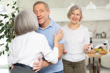 Obraz premium Two elderly couples meet for a holiday dinner at home. Greet each other