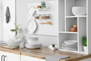 Plates, bowls and glasses on table near white wall in kitchen