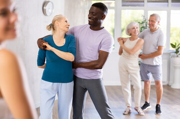 Happy smiling elderly woman enjoying impassioned merengue with african american partner in latin...